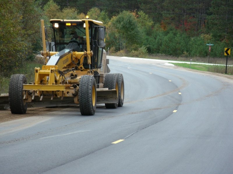 Road grater leveling road shoulder